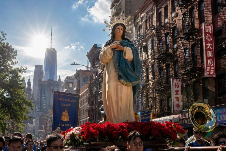 En statue af Vor Frue bæres i procession gennem en gade i New York.