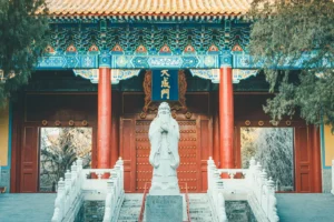 Tradisjonell arkitektur med Confucius-statue ved inngangen til et tempel i Beijing.