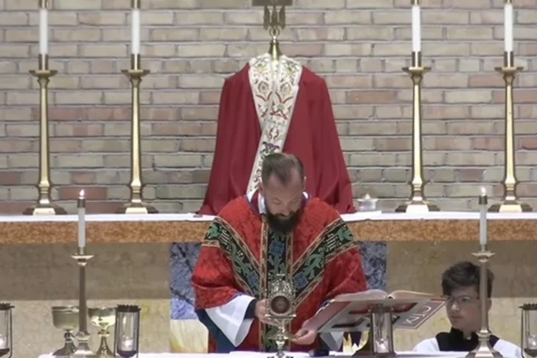 Pastor Brent Bowman står med bøjet hoved under den eukaristiske bøn ved en skolemesse i St. Gabriel the Archangel Catholic Church.