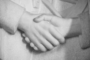 Nærbilde av et skulpturelt håndtrykk hugget i stein, som symboliserer enhet og enighet.