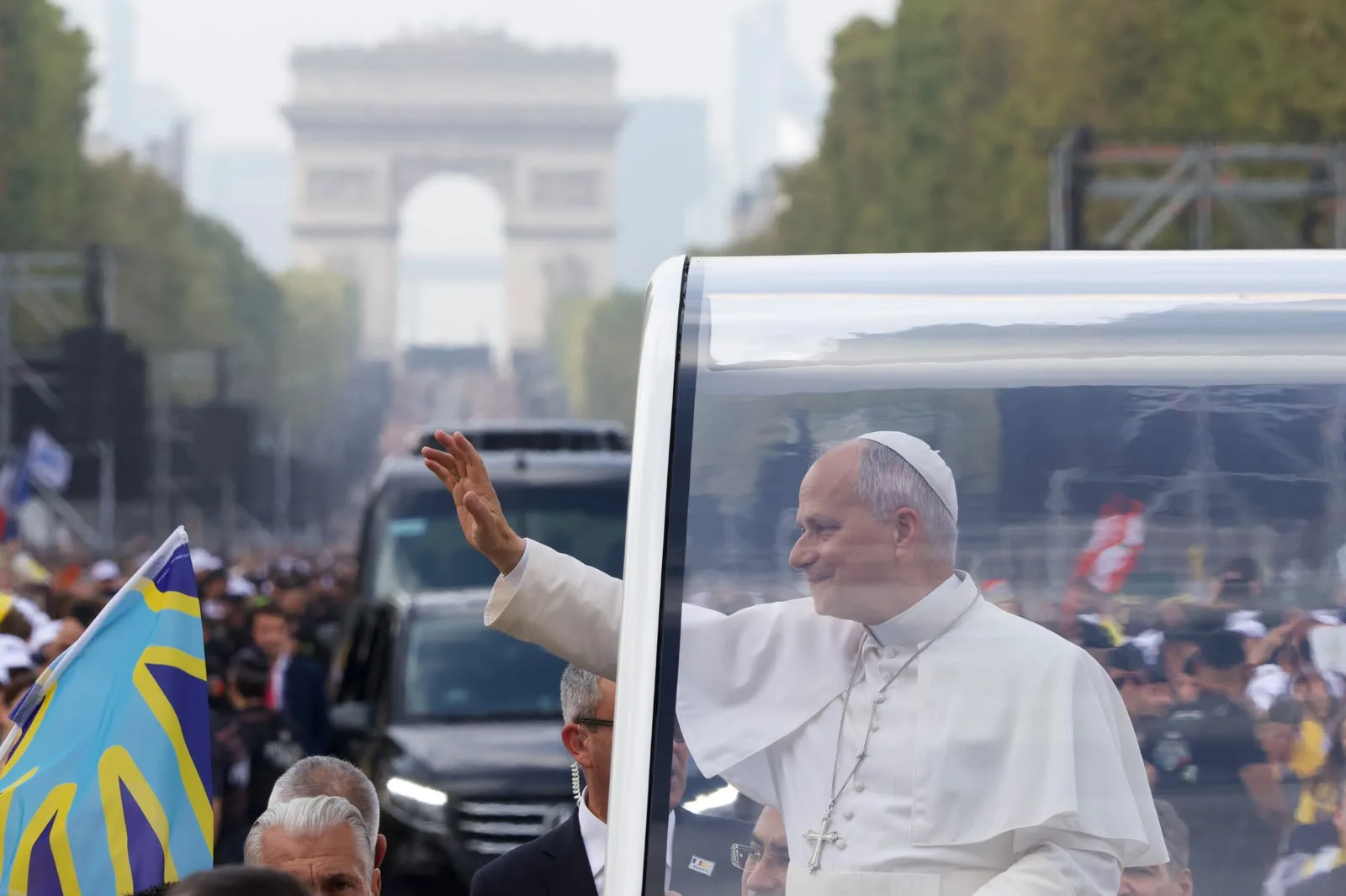 Pave Leo XIV vinker fra pavemobilen på Avenue des Champs-Élysées.
