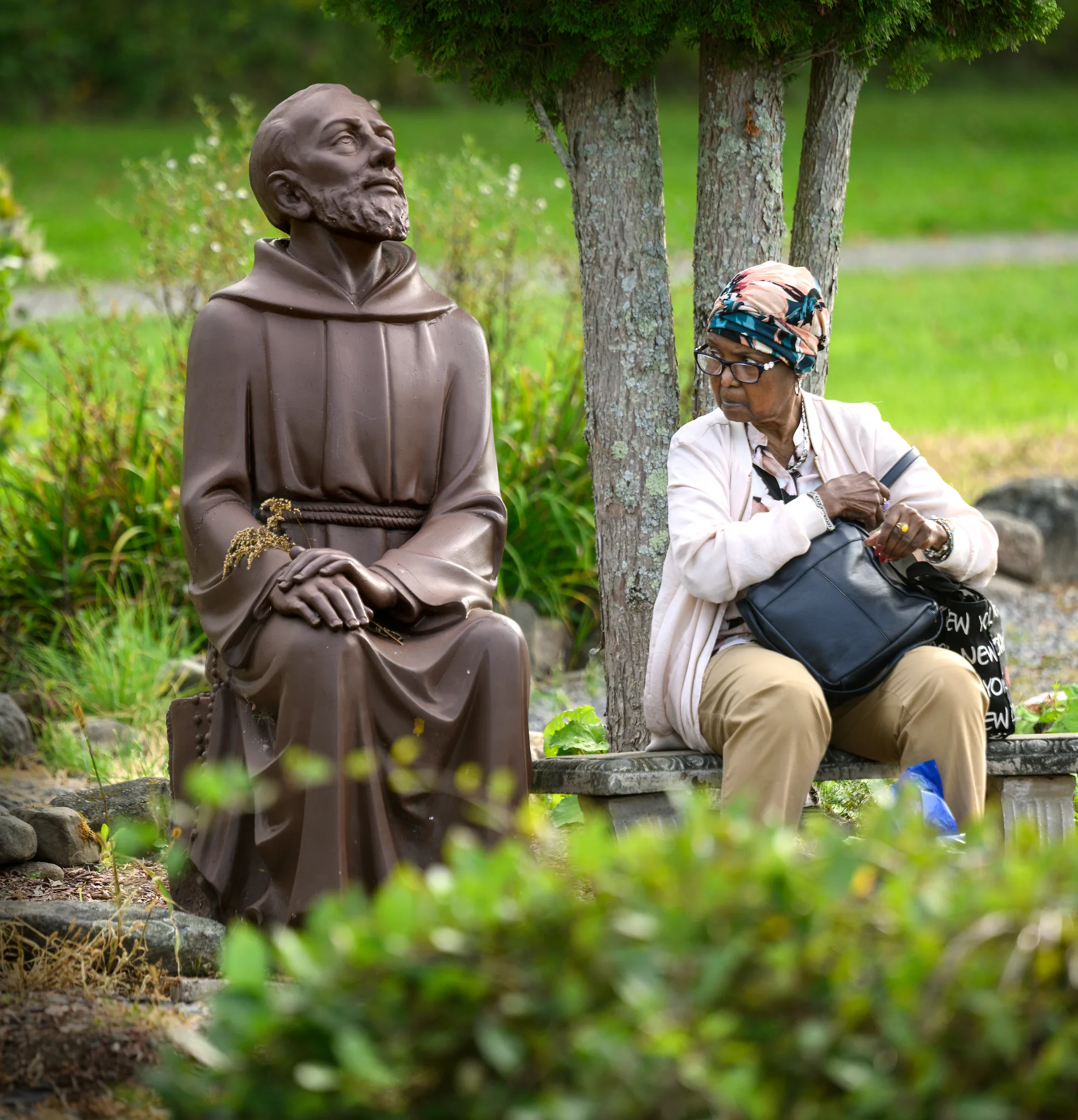 Gielle Antoine sidder ved en statue af Padre Pio.