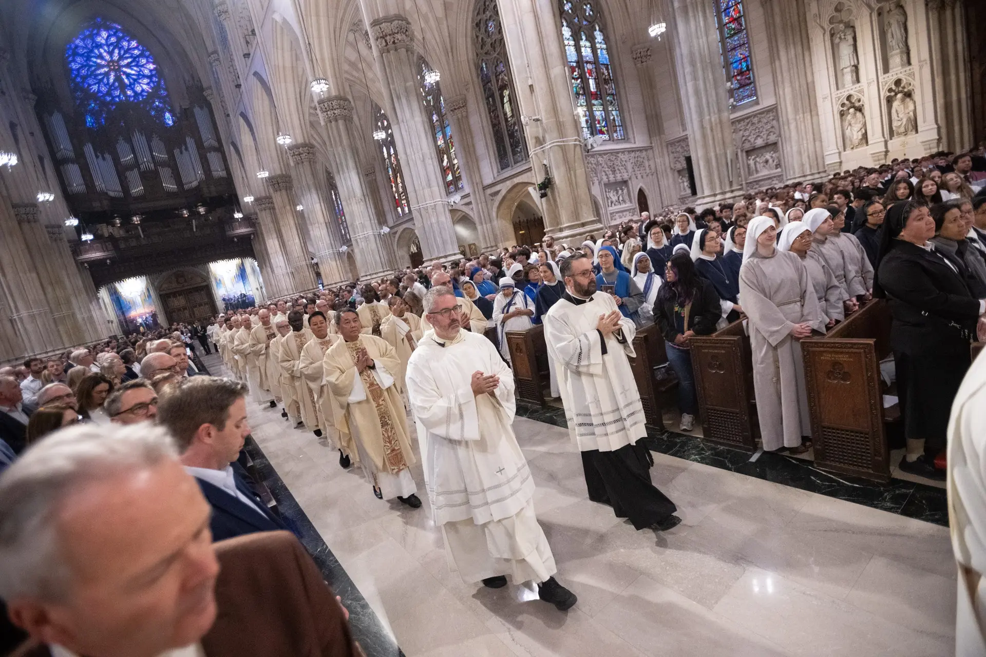 Præster bevæger sig gennem en tætpakket katedral.