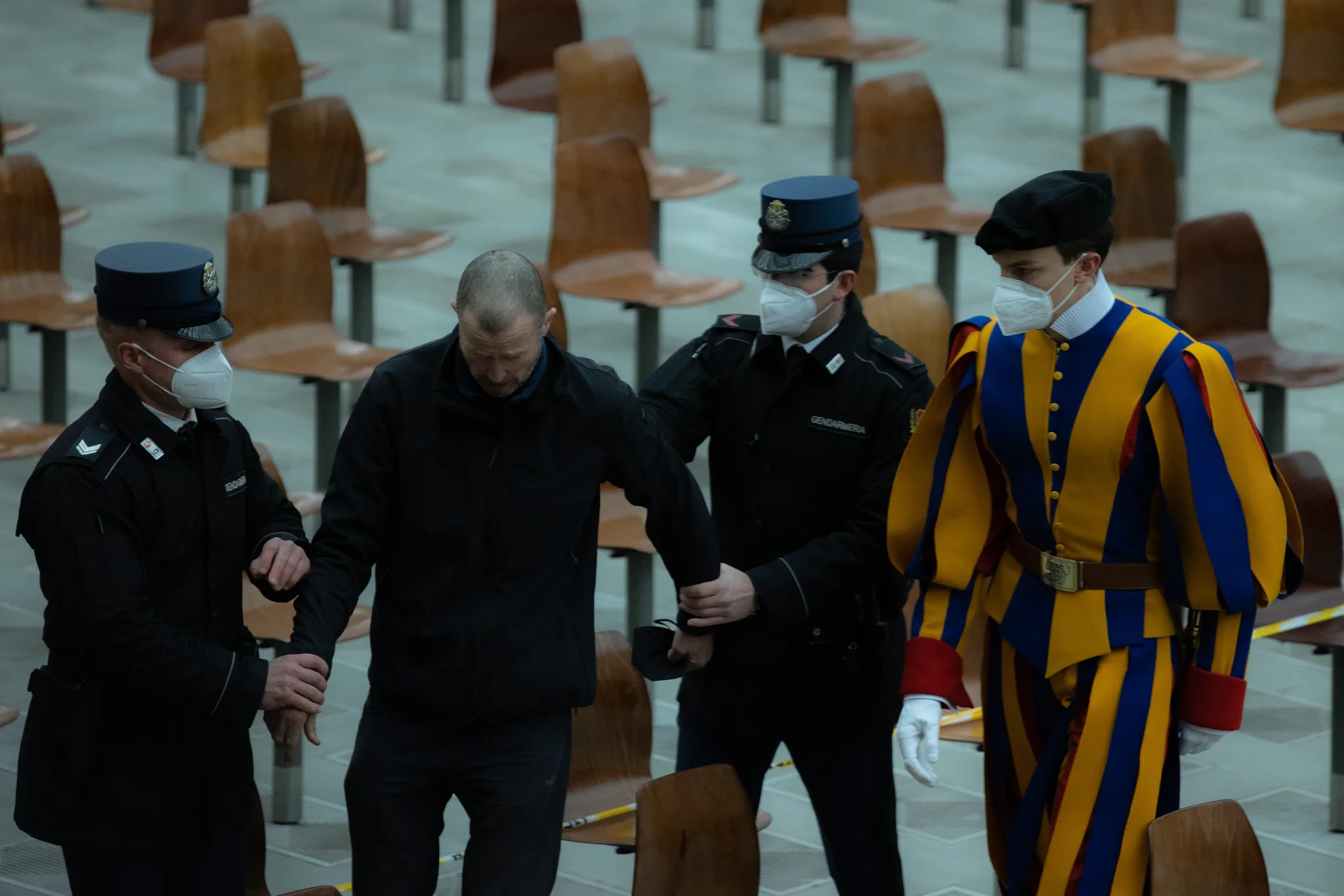 Vatikanets gendarmer og en schweizergardist fører en mand ud af Paul VI-salen.
