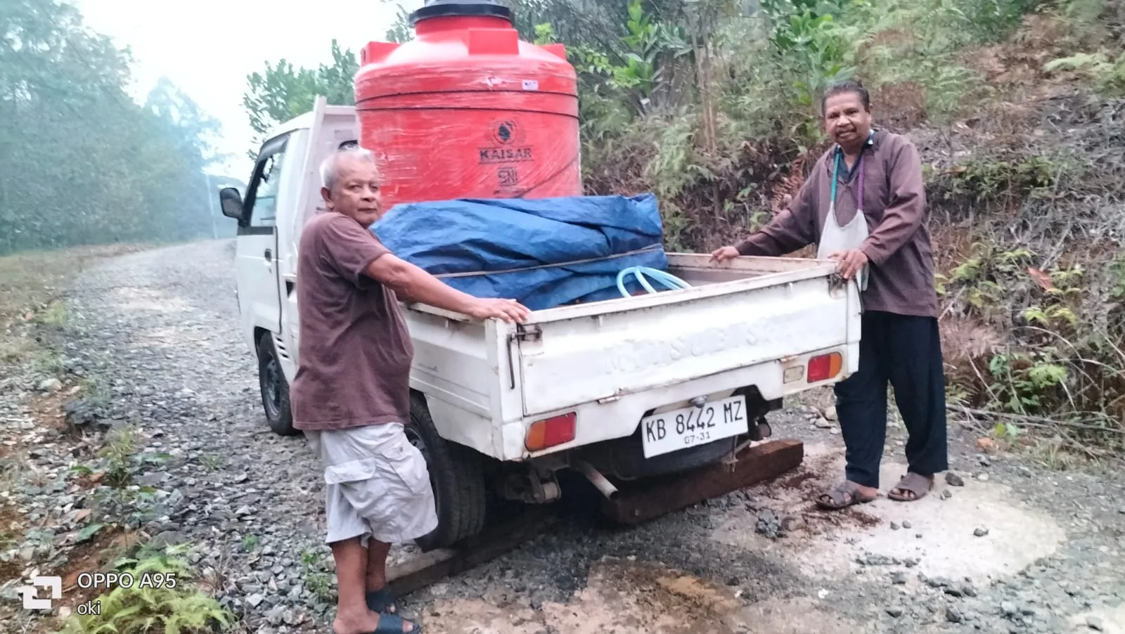 Mænd læsser en vandtank op på en pickup i Kalimantan.