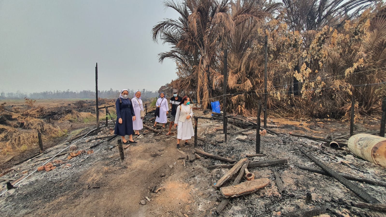 Katolske ordenssøstre og frivillige ved et brandødelagt hus i Kalimantan.